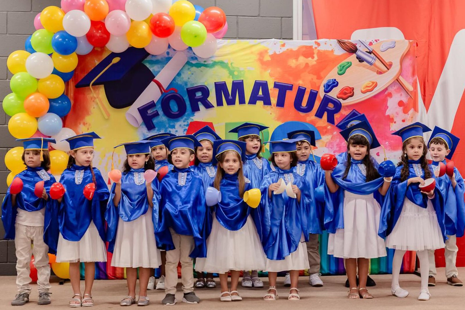 Formatura com becas azuis e balões coloridos